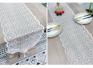 Macro detail of white lace table runner with intricate floral patterns and fringe tassels