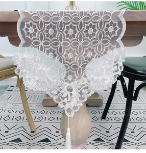 Detailed view of white lace table runner featuring floral embroidery and elegant tassels