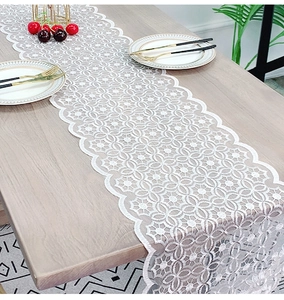 Close-up of white lace table runner with geometric floral patterns and wavy edges
