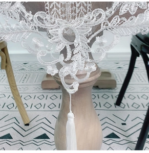 Macro shot of white lace table runner with floral embroidery and tassel detail