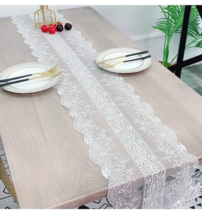 Detailed view of white lace table runner with intricate floral embroidery on wooden table
