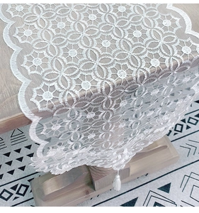 Close-up of white lace table runner with hollow floral patterns and silk tassel fringe