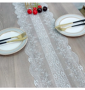Close-up of white lace table runner with floral embroidery and elegant scalloped edges