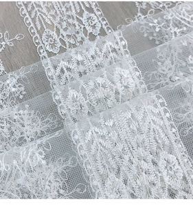 Macro detail of elegant white lace fabric with intricate floral embroidery patterns