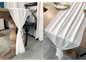 Detail of white chiffon table runner with elegant folds and ribbon ties on wood table