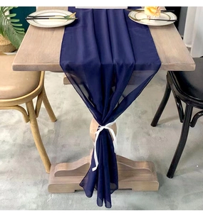 Detail of dark blue chiffon table runner with white silk ribbon on a wooden table