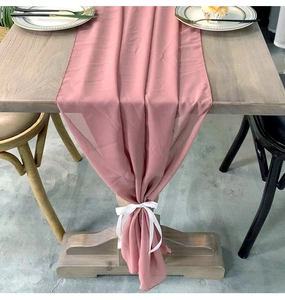 Detail of dusty pink chiffon table runner with white ribbon on a wooden table set