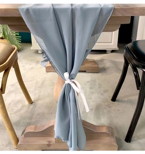 Detail of elegant dusty blue chiffon table runner with decorative white silk ribbon tie