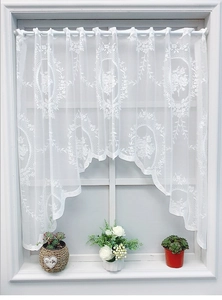 Detail of white lace window valance with classic floral embroidery and scalloped edges