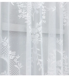 Close-up of white lace curtain fabric showing intricate floral jacquard patterns