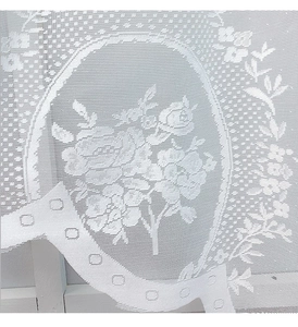 Close-up of white floral lace curtain with rose patterns and scalloped wave edges