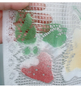 Macro detail of white lace mesh fabric featuring colorful fruit prints and texture