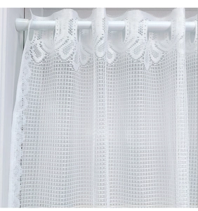 Detailed macro of white lace kitchen curtain with floral patterns and rod pocket design