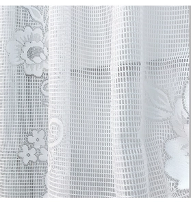 Dettaglio della tenda in pizzo bianco con ricami floreali e maglia esagonale fine