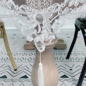 White embroidered lace table runner with elegant floral patterns and tassel trim decor