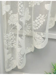 Detail of white lace kitchen curtain showing rose jacquard patterns and scalloped edges