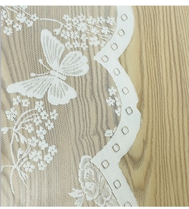 Detail of white Nordic lace curtain with butterfly patterns on a rustic wooden background