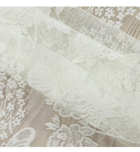 Detailed close-up of white lace kitchen curtain featuring intricate rose embroidery