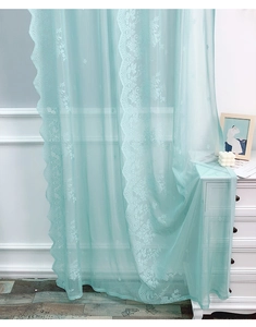 Dettaglio di tenda in pizzo verde menta con ricami floreali e bordo smerlato elegante