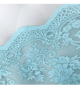 Dettaglio del ricamo in pizzo floreale azzurro con eleganti bordi a forma di festone
