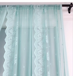 Dettaglio della tenda in pizzo azzurro con ricami floreali e bordo a onde elegante