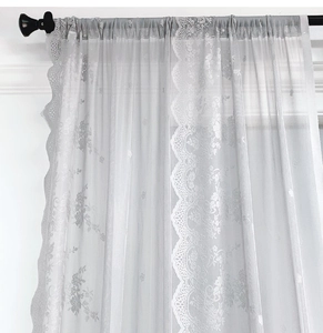 Dettaglio della tenda in pizzo bianco con ricami floreali e bordi smerlati eleganti