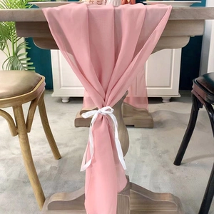 Light pink chiffon table runner with white ribbons for elegant wedding decor on wooden table