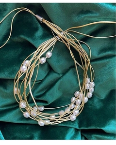 Detail showing elegant multi-strand pearl curtain tieback on green velvet fabric