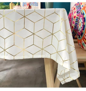 Detail of white velvet tablecloth with golden geometric hexagonal lines on a wooden table