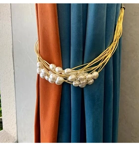 Close-up of elegant curtain tieback with white pearls and braided golden wires
