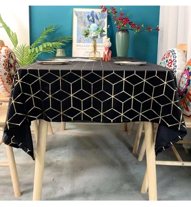 Detail of dark velvet tablecloth featuring luxury gold geometric cube patterns for dining decor