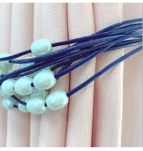 Detail of elegant navy braided cord curtain tieback with white oval pearl beads