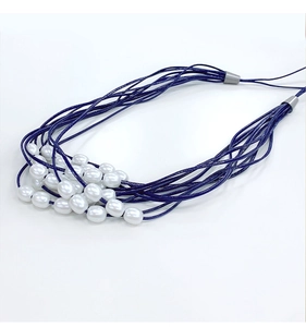 Detail of elegant navy blue cord curtain tieback with polished white oval pearls