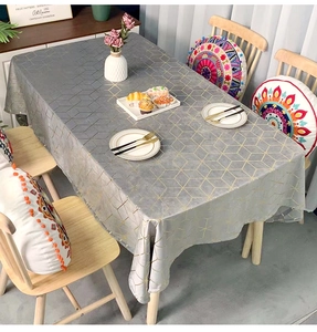 Detailed close-up of a grey velvet tablecloth with golden geometric patterns on a wooden table