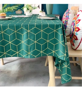Macro detail of dark green velvet tablecloth with gold geometric cube pattern on a table
