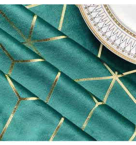 Close-up of dark green velvet tablecloth with gold geometric patterns and a dinner plate