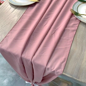Elegant dusty rose chiffon table runner with white ribbon ties on a wooden table