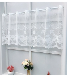 Close-up of white lace cafe curtain with floral crochet pattern and scalloped edges