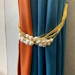 Elegant multi-strand gold wire curtain tieback with white pearls on modern drapes