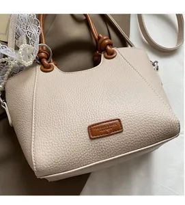 Détail du sac beige texture litchi avec poignée en cuir marron nouée et boucles argentées