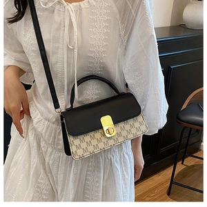 Détail du sac bandoulière avec rabat en cuir noir, motif M et fermoir rotatif doré