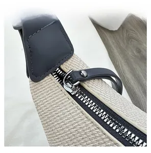 Detailed macro view of silver metal zipper and dark gray leather puller on woven bag