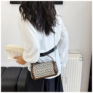 Detail of a brown cylindrical bag with silver rhinestones and a metal chain strap