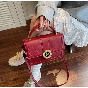Detail of red quilted leather handbag with gold M-logo buckle and structured flap design