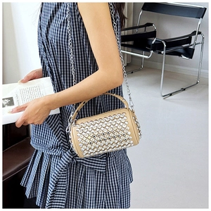 Detail view of rhinestone-studded cylinder bag with metallic chain and leather handle