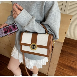 Detail of quilted two-tone crossbody bag with gold metal logo and Greek key patterns