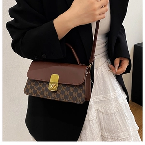 Detail view of the vintage monogram pattern and gold metal twist lock on a shoulder bag