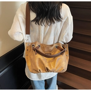 Detail view of the caramel tote bag with metal eyelets and adjustable fabric strap
