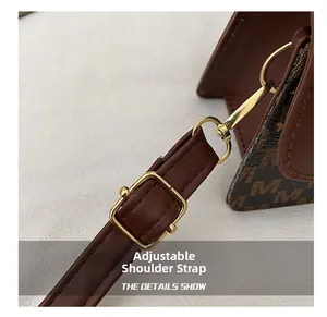 Detail of adjustable leather shoulder strap with gold metal buckle and M-pattern embossing