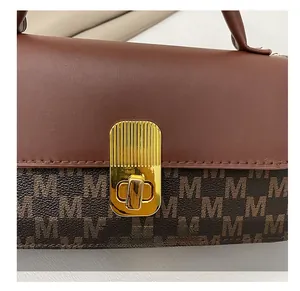 Detailed macro view of the golden metal twist lock on a brown leather shoulder bag